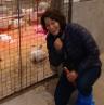 Kirstie kneeling by the broilers' room in Ag facilities at CEP campus.